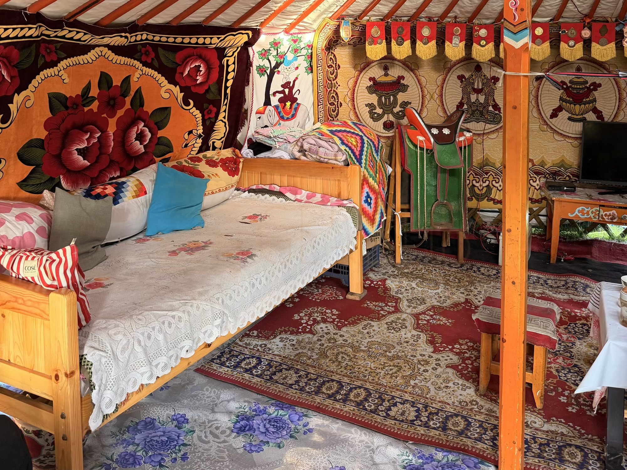 Chuluunbaatar racehorse trainer camp: One of the two beds inside the guest ger, decorated with the traditional painted wood common to this region. (Guest bed)