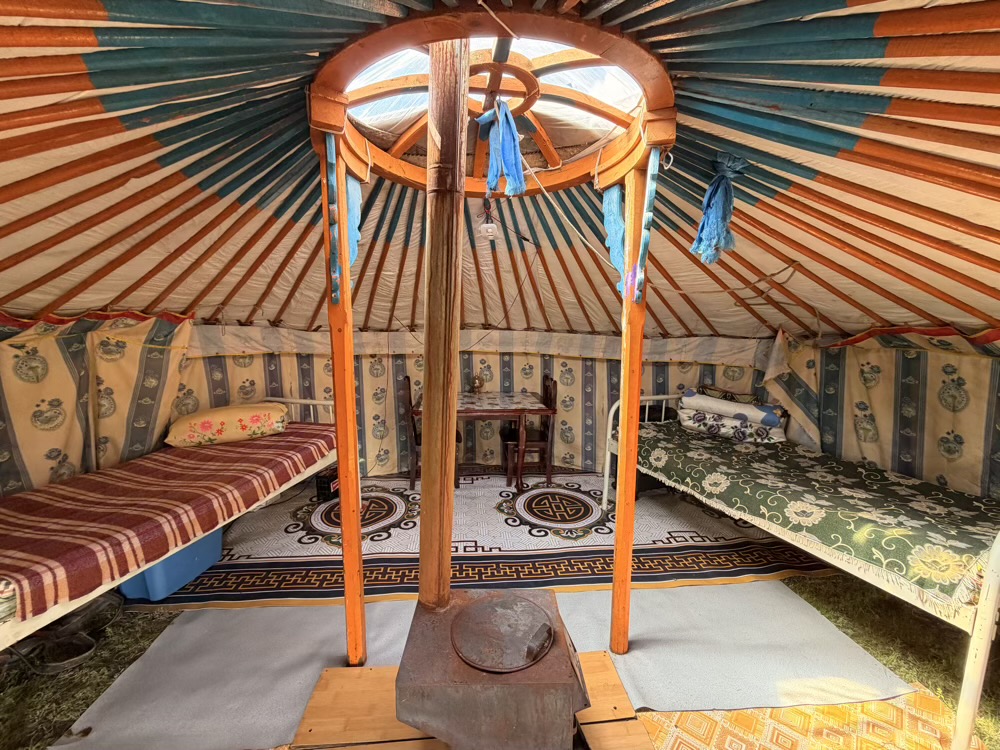 Myagmarsuren khuushuur camp: Inside the ger: a practical space designed for both resting and working, equipped with heavy insulation and a central wood stove. (Interior, Bedding, Stove)